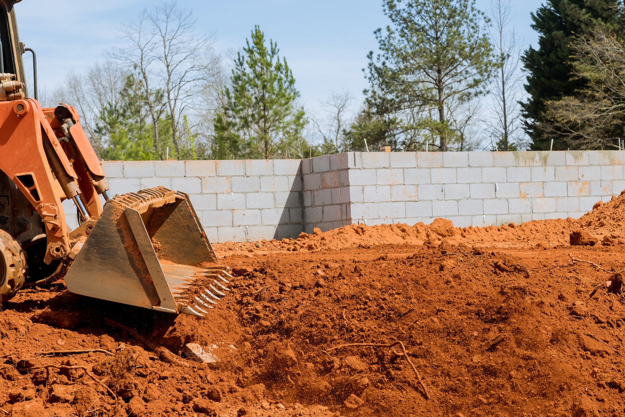 An excavator scoop is moved and aligned as it moves along the land at a construction site